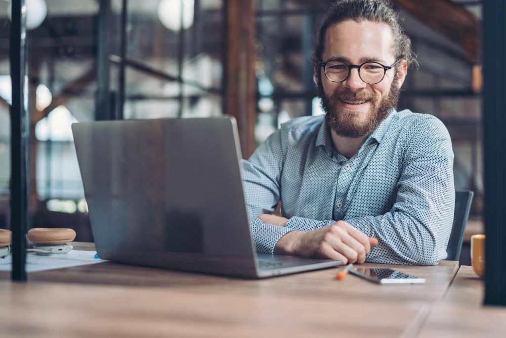 Adult business man with a laptop smiles while wearing braces as an adult