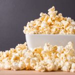 Popcorn, which is a food to avoid with braces, in a white bowl against a gray wall