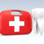 A white tooth floats next to a red and white emergency first aid kit
