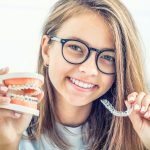 orthodontic treatment options, Dental invisible braces or silicone trainer in the hands of a young smiling girl. Orthodontic concept - Invisalign.